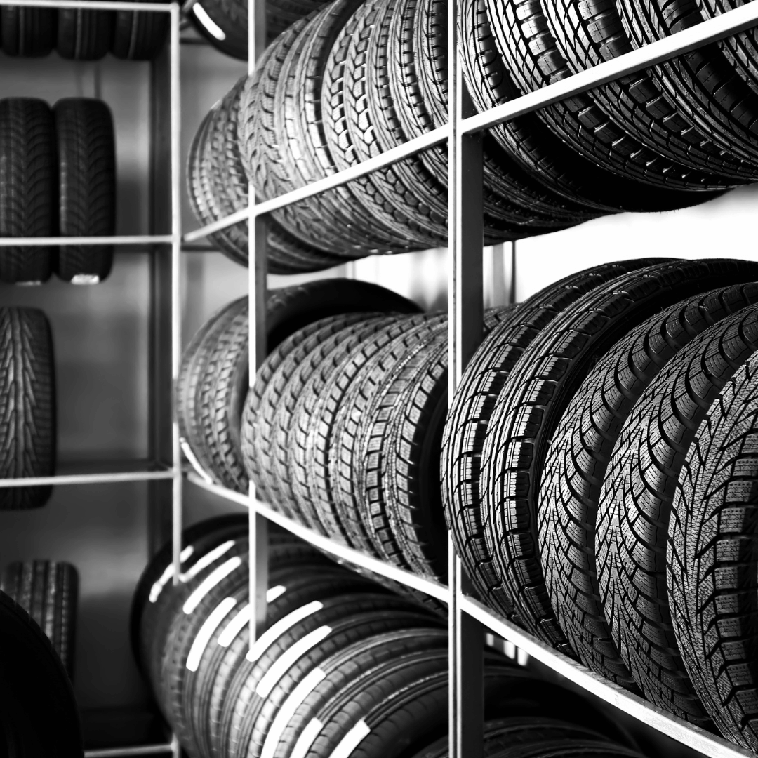 Classic tire rack featuring three rows of tires, captured in a striking black and white image. A timeless display showcasing our diverse tire selection and commitment to quality automotive essentials.